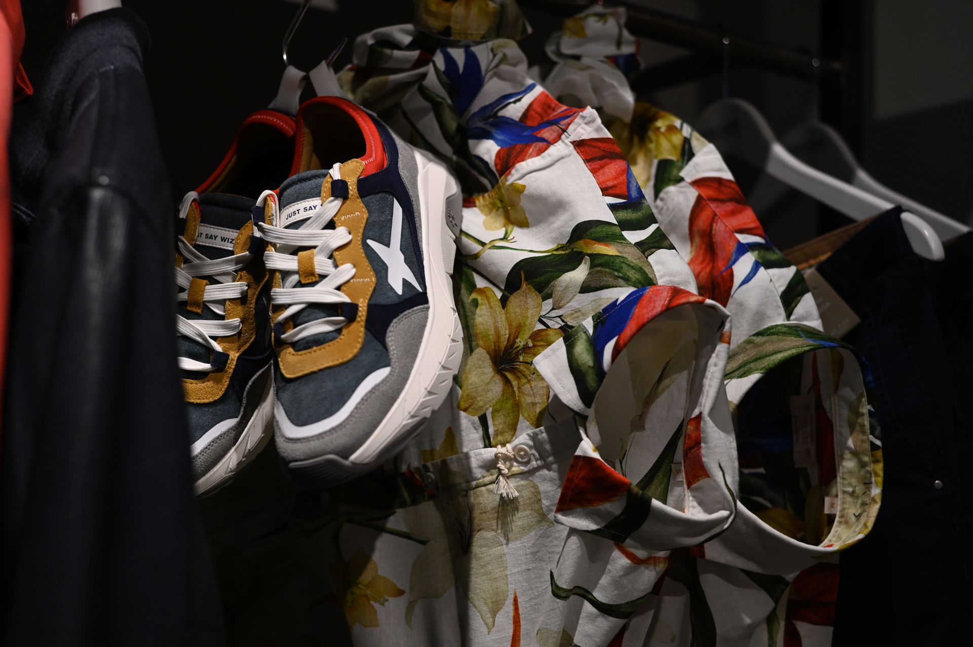 Un paio di scarpe da ginnastica appese a un attaccapanni accanto a una camicia a fiori.