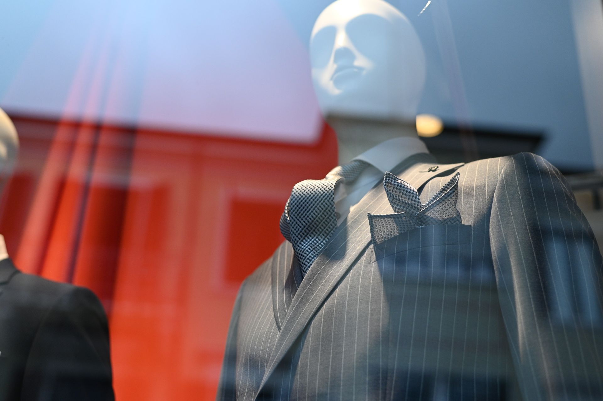 Un manichino indossa un abito e una cravatta nella vetrina di un negozio.