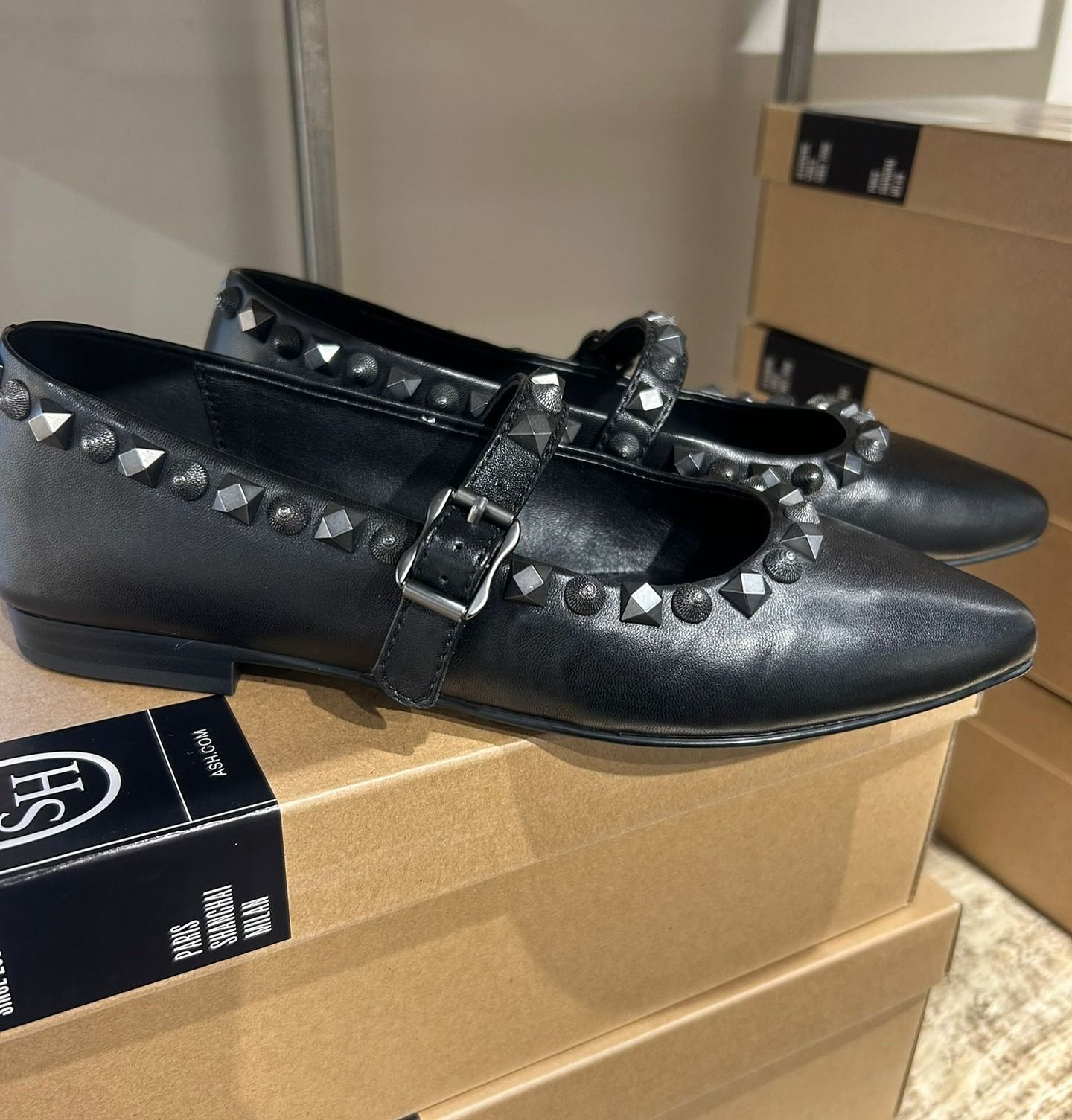 Ballerine nere borchiate sopra scatole di cartone.