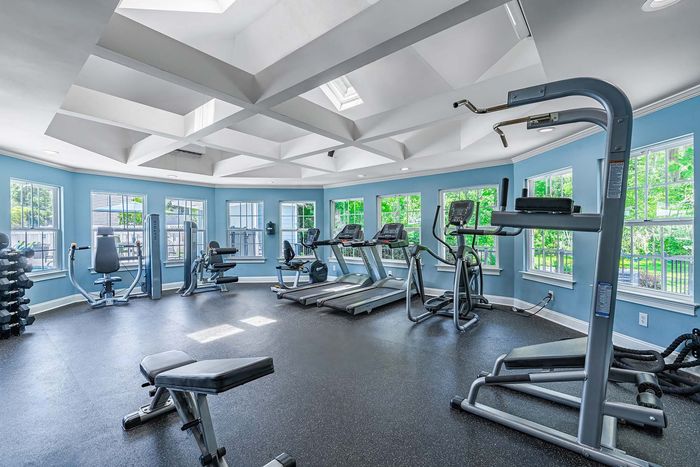 Gym with exercise equipment, blue walls, white ceiling, and large windows.
