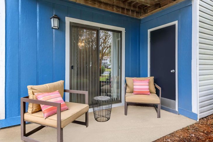 Blue patio with two chairs, a small table, and a sliding glass door.