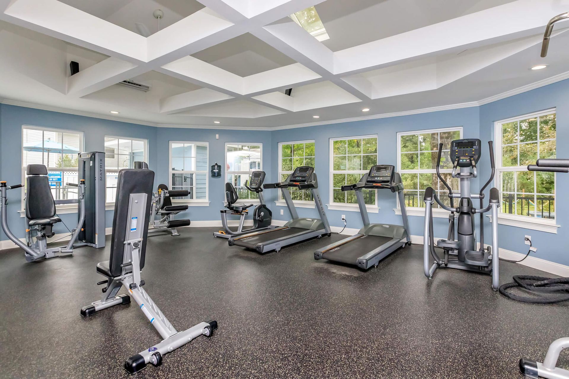 Gym with exercise equipment, blue walls, and windows.