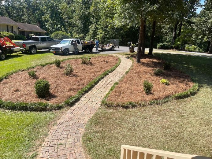 A brick walkway leading to a house with trucks parked in the driveway.