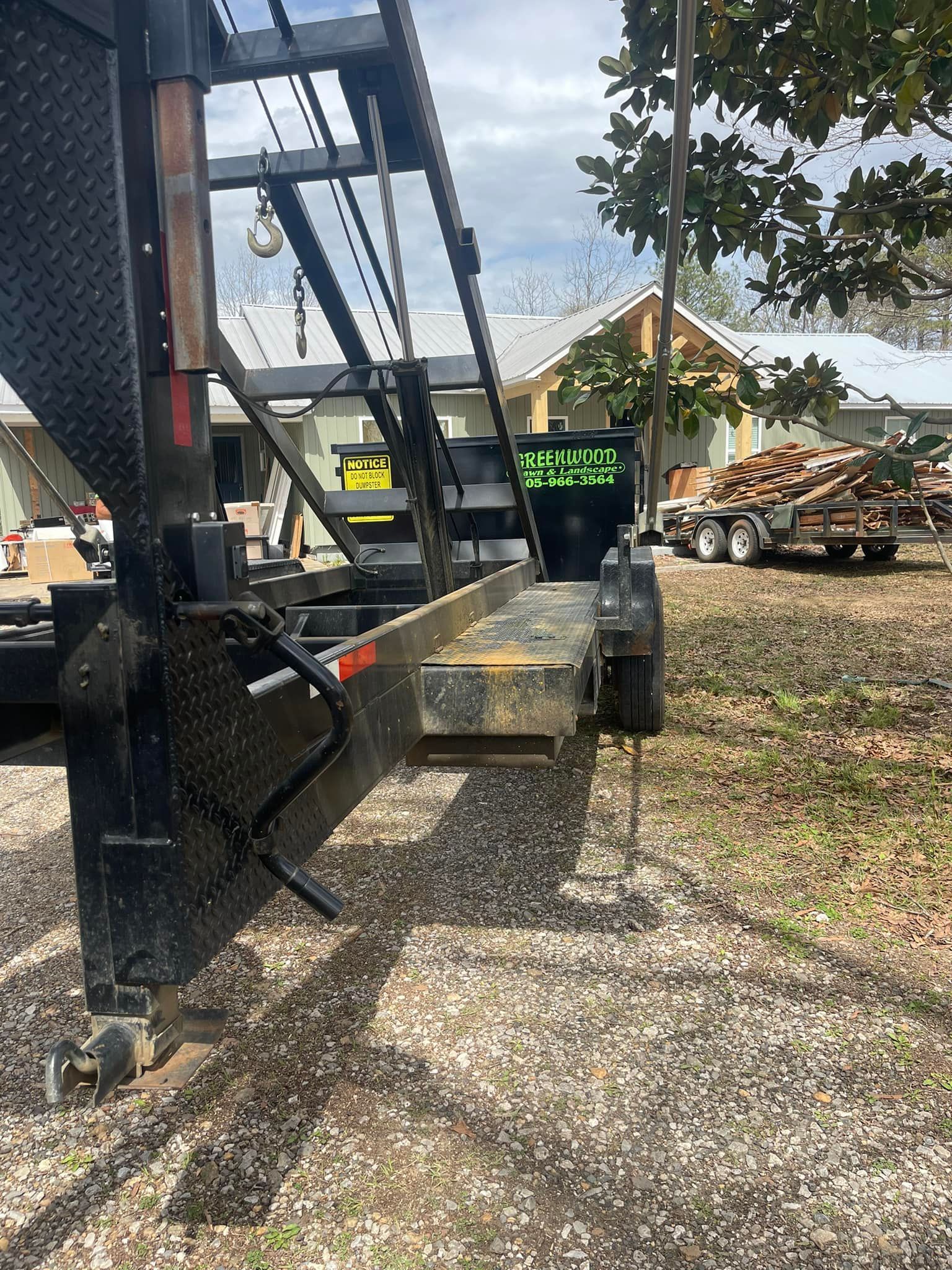 A trailer is parked in a gravel lot in front of a house.