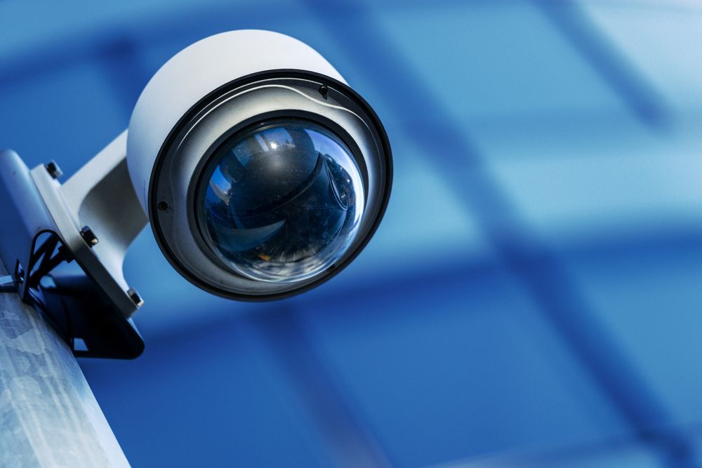 Person Installing a Security Camera on a Building's Overhang — INtelephony In Albury, NSW