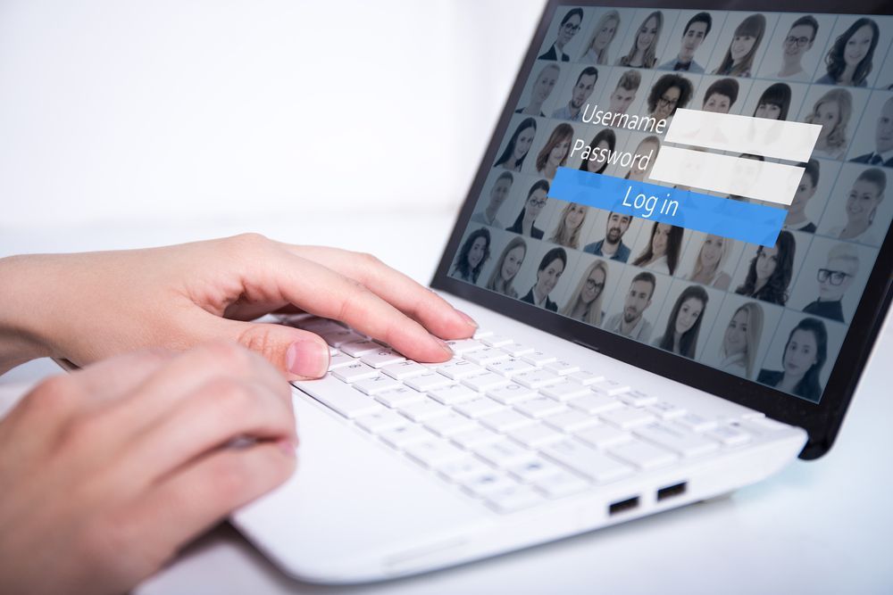 Hands Typing on a White Laptop Showing a Login Screen With User Profile — INtelephony In Albury, NSW