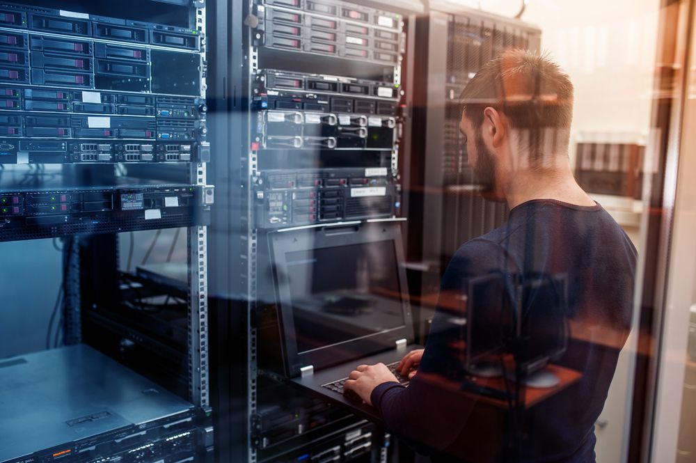 Man Working on a Laptop in a Server Room — INtelephony In Albury, NSW