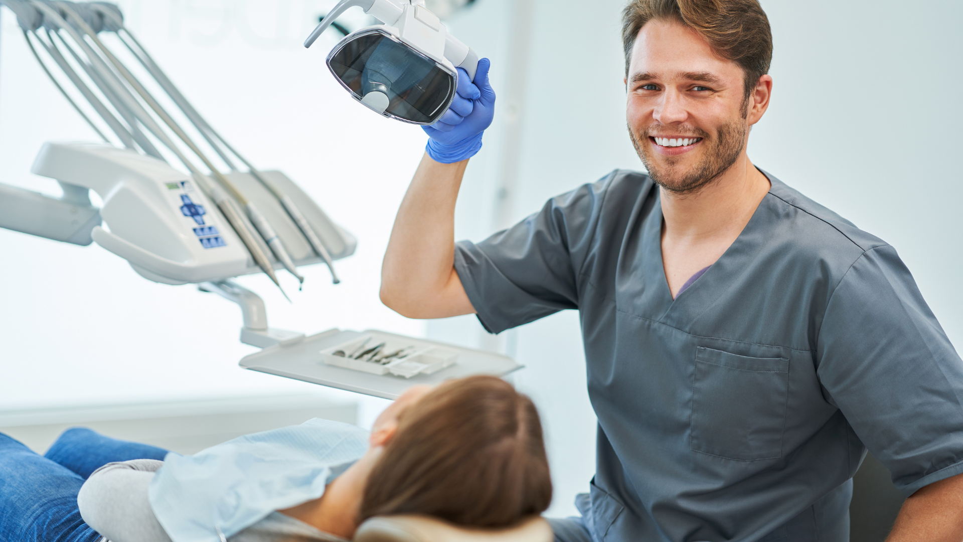 A dentist is talking to a patient in a dental chair.