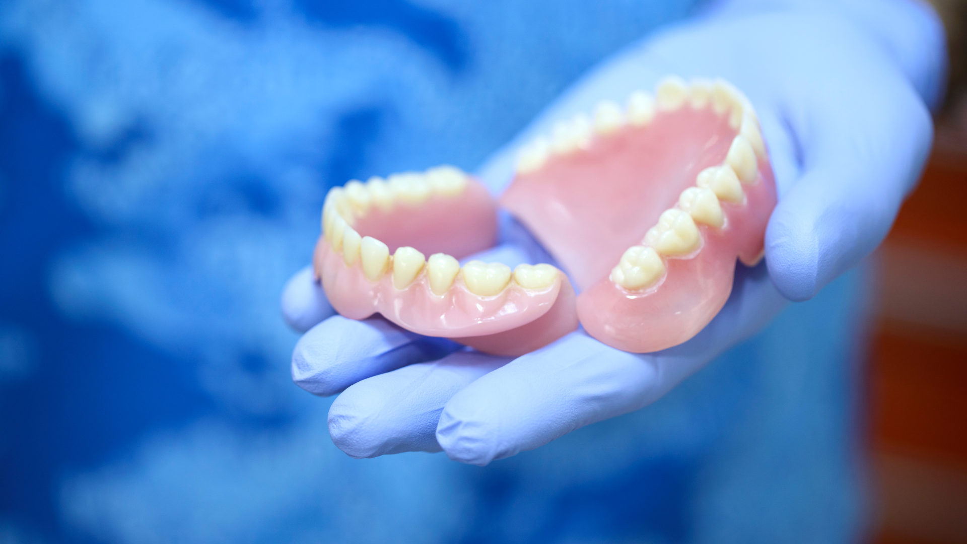 A person is holding a pair of dentures in their hands.