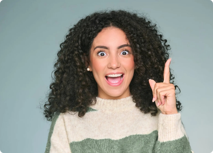 a woman with curly hair is pointing up with her finger .
