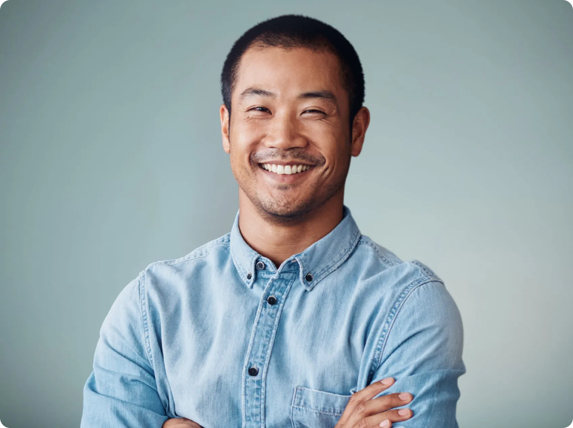 a man in a blue shirt is smiling with his arms crossed .