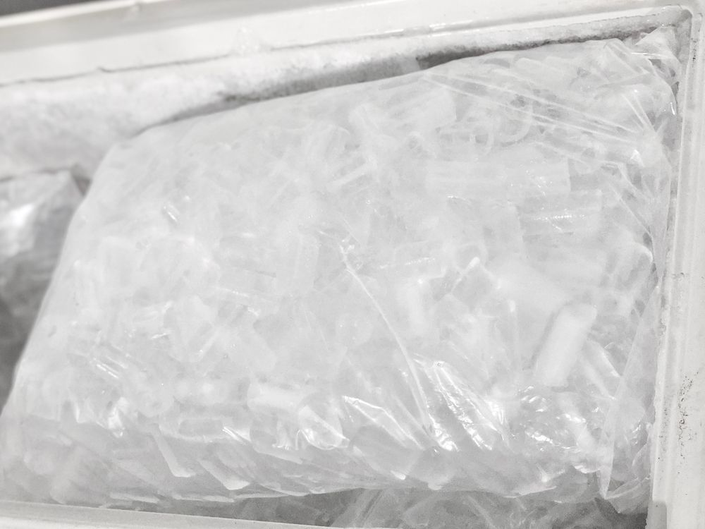 A Clear Plastic Bag Filled With Ice Cubes Sitting Inside a Freezer Bin — Cool Blue Ice & Water in Tamworth, NSW