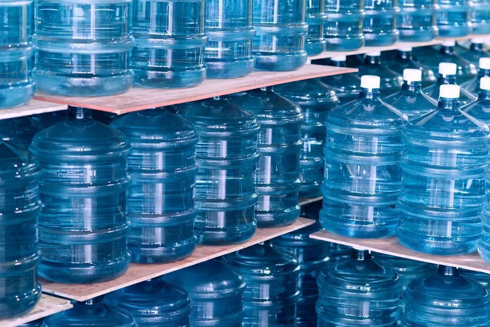 Rows of Large, Blue Plastic Water Jugs Stored on Wooden Shelving in a Warehouse — Cool Blue Ice & Water in Gunnedah, NSW