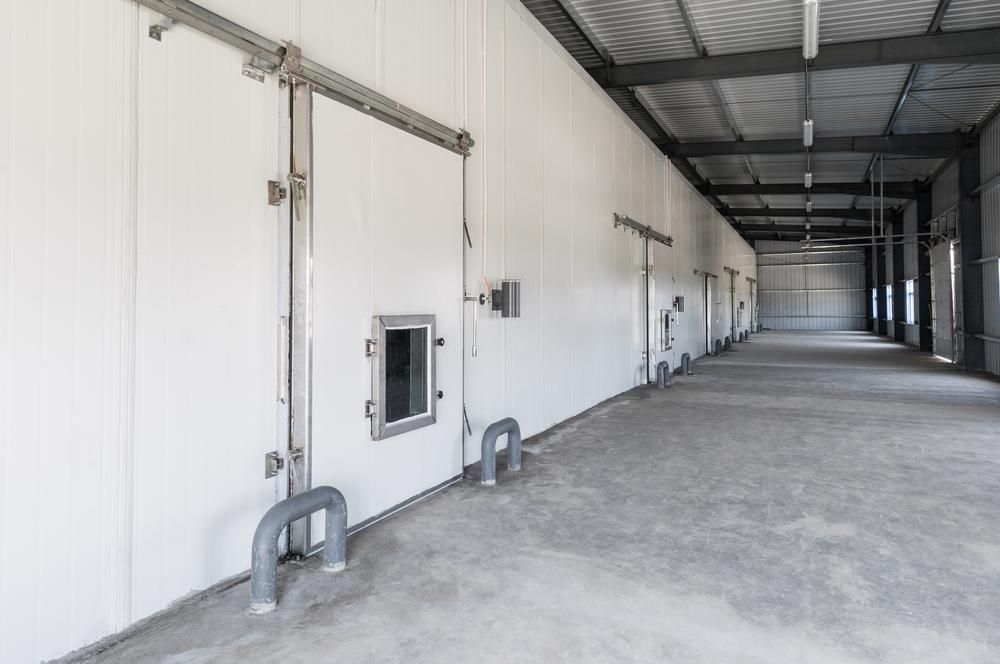 A Long, Empty Warehouse Corridor With White Insulated Walls and Large Sliding Doors — Cool Blue Ice & Water in Mudgee, NSW