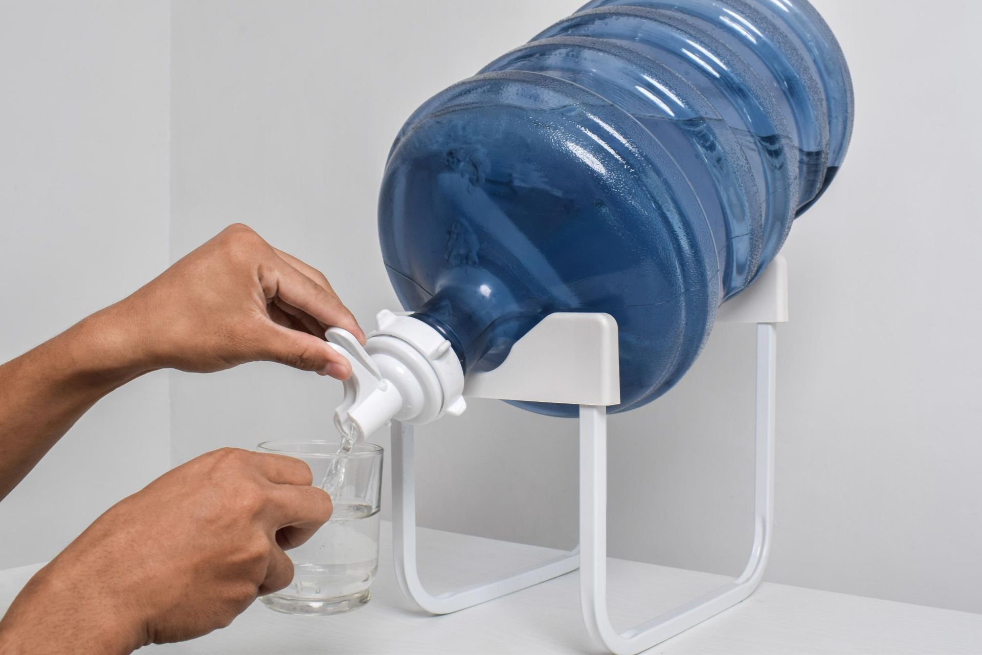 A Person Uses a White Plastic Valve on a Large Water Jug — Cool Blue Ice & Water in Murrurundi, NSW