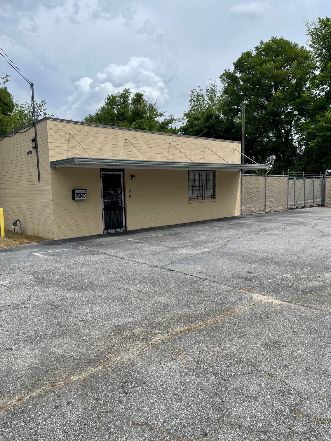 A small brick building with a parking lot in front of it.