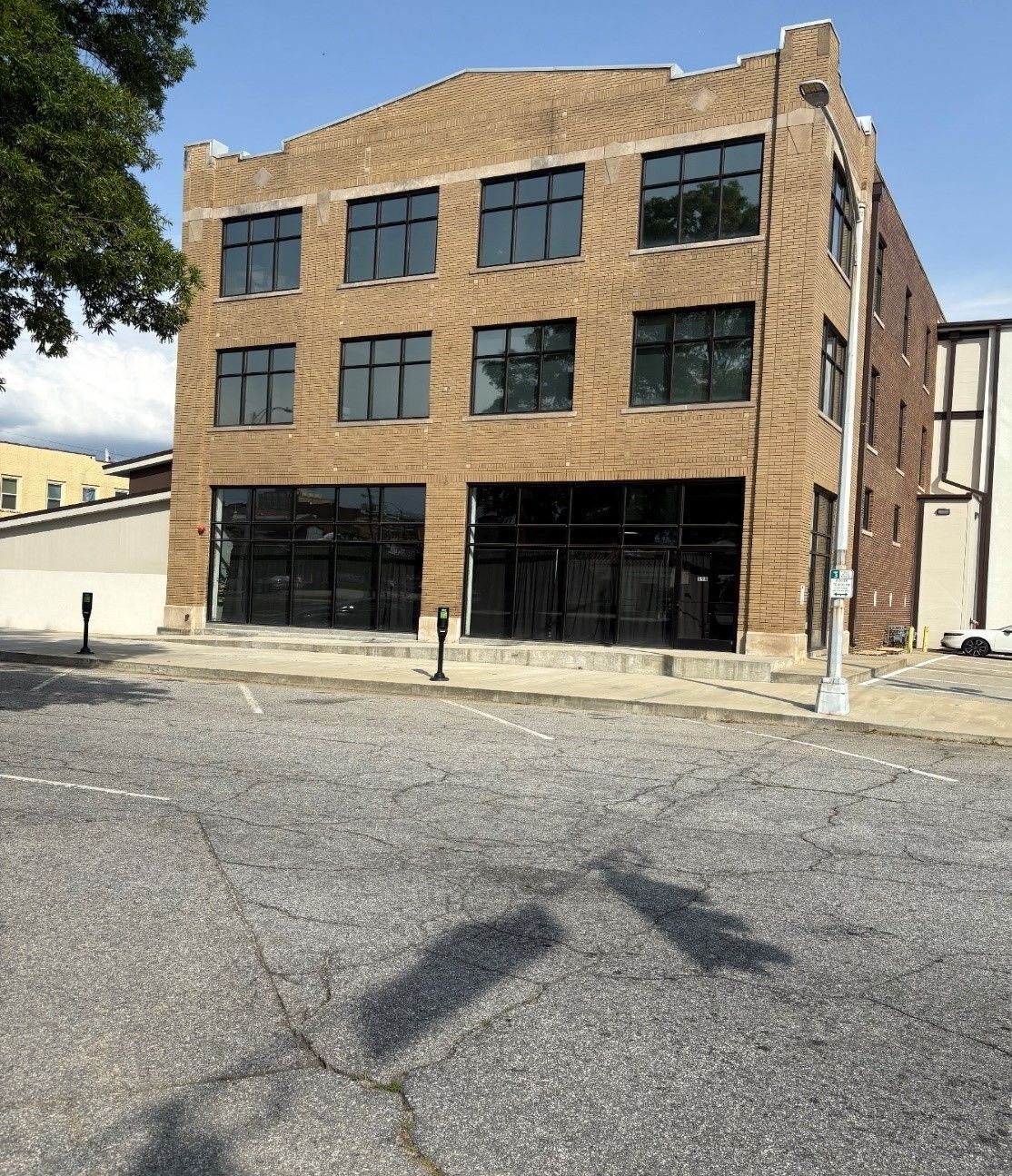 A large brick building with a lot of windows and a parking lot in front of it
