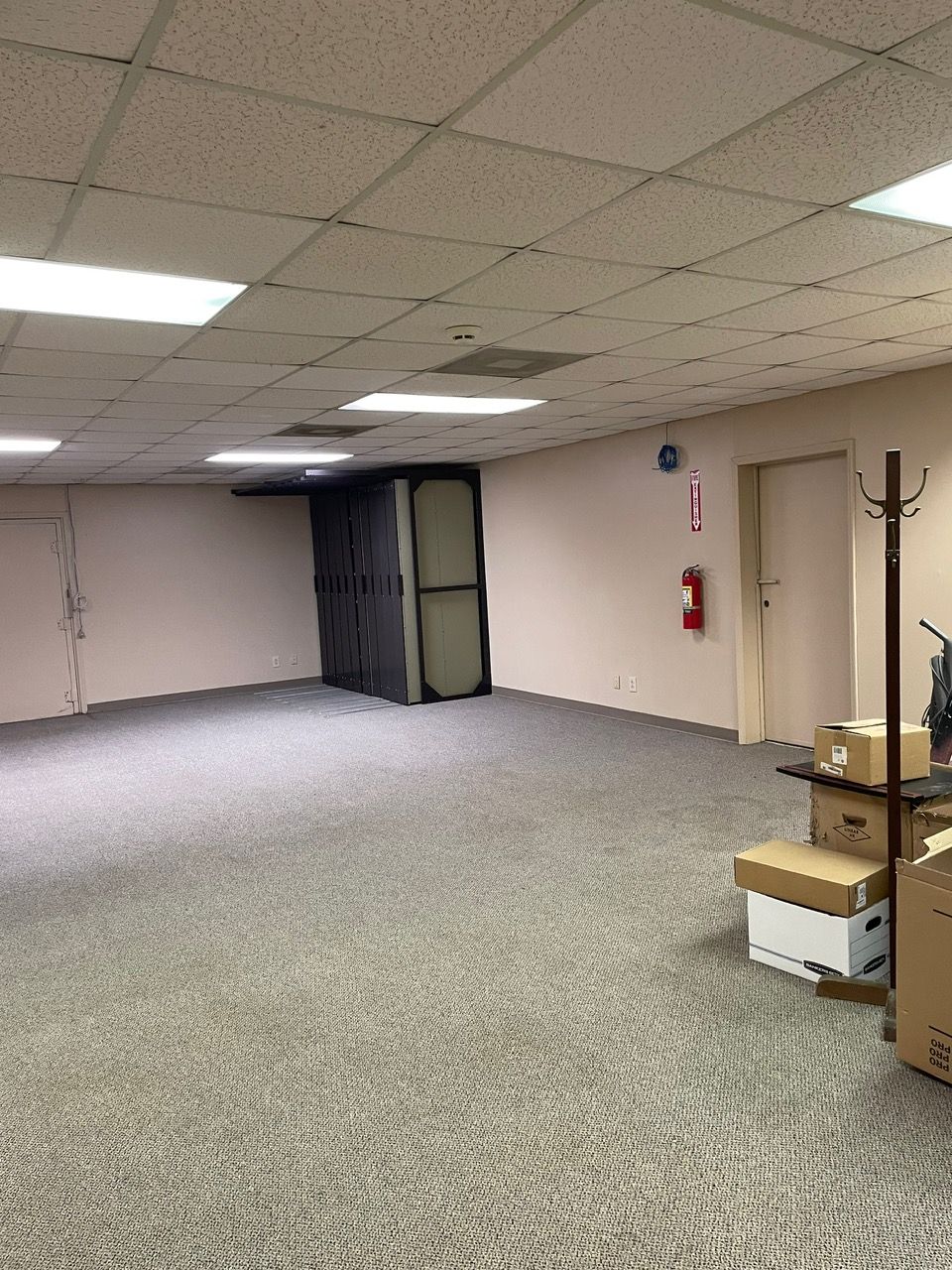 An empty room with boxes on the floor and a fire extinguisher on the wall.