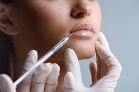 A woman is getting a filler injection in her lips.