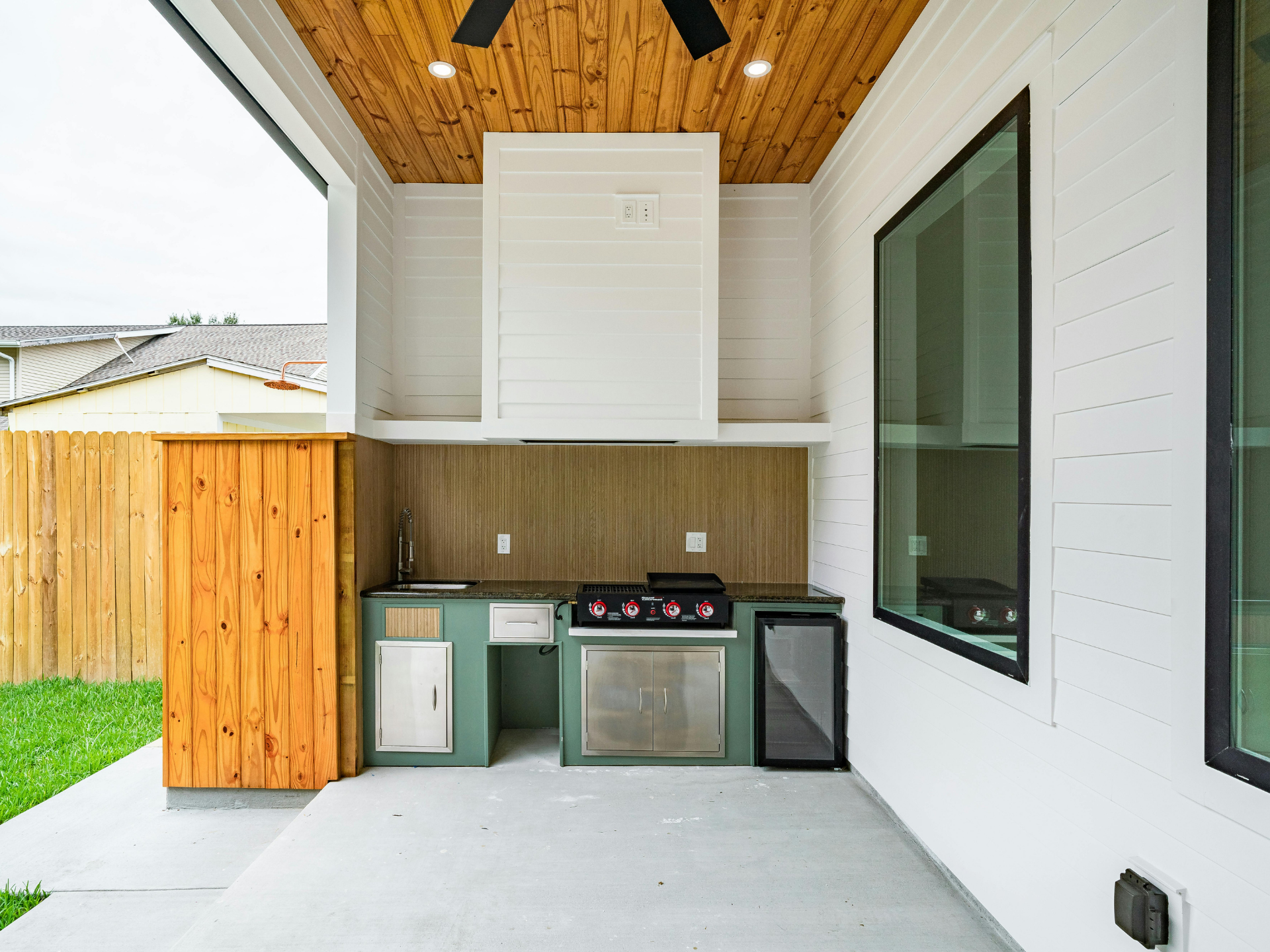 A kitchen with a stove , sink , refrigerator and a ceiling fan.