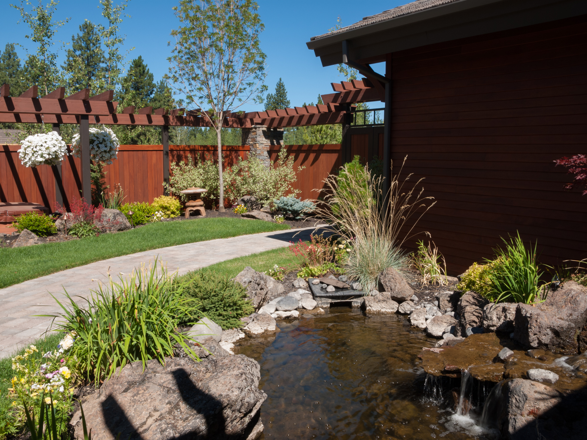 A pond with a waterfall in the backyard of a house