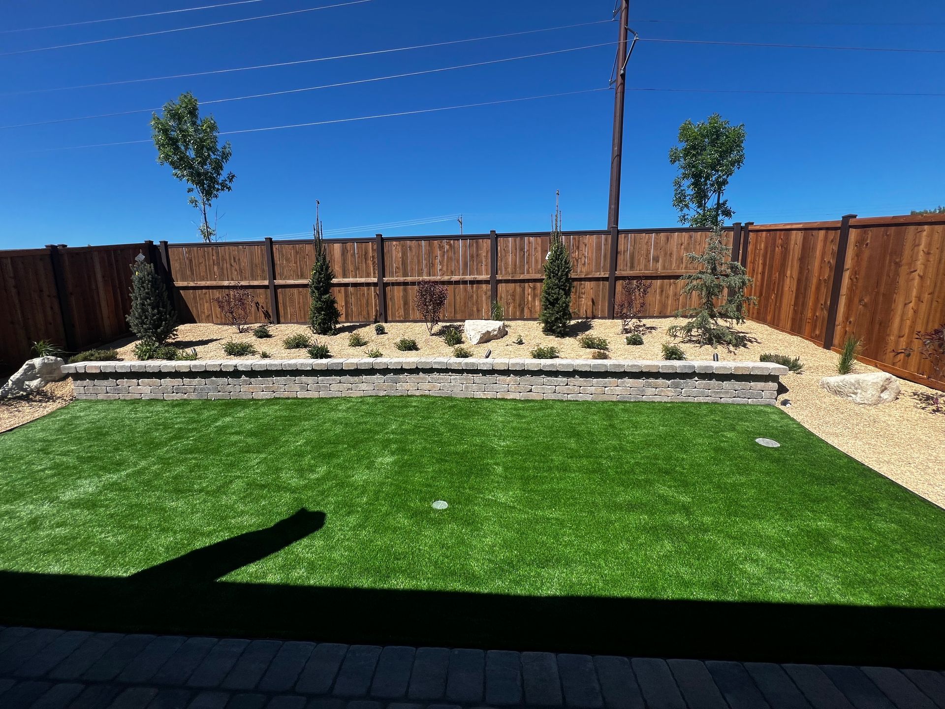 A backyard with a wooden fence and a lush green lawn.