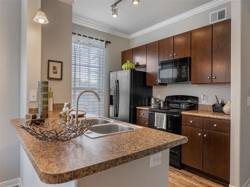 Kitchen with dark brown cabinets, black appliances, and granite countertops.