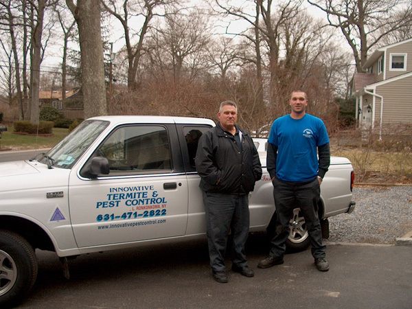 two men standing next to a termite pest control truck