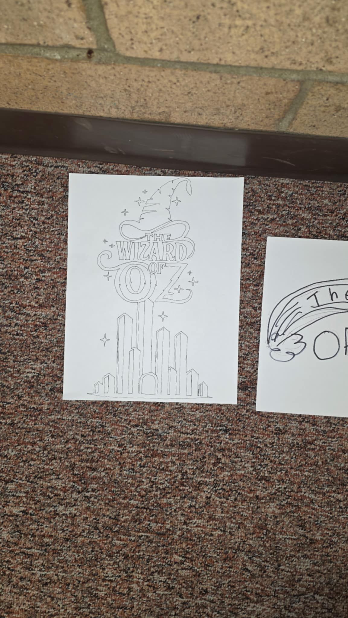 Two drawings on white paper: cityscape and vehicle outline.