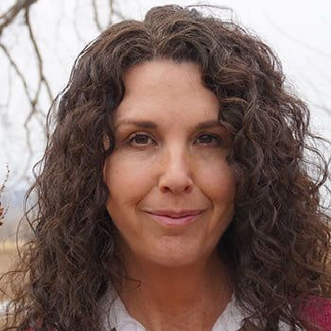 A woman with curly hair is smiling for the camera.