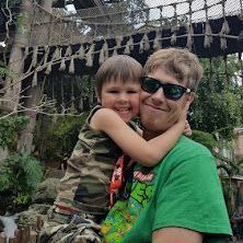 A man in a green shirt is holding a little boy in his arms.