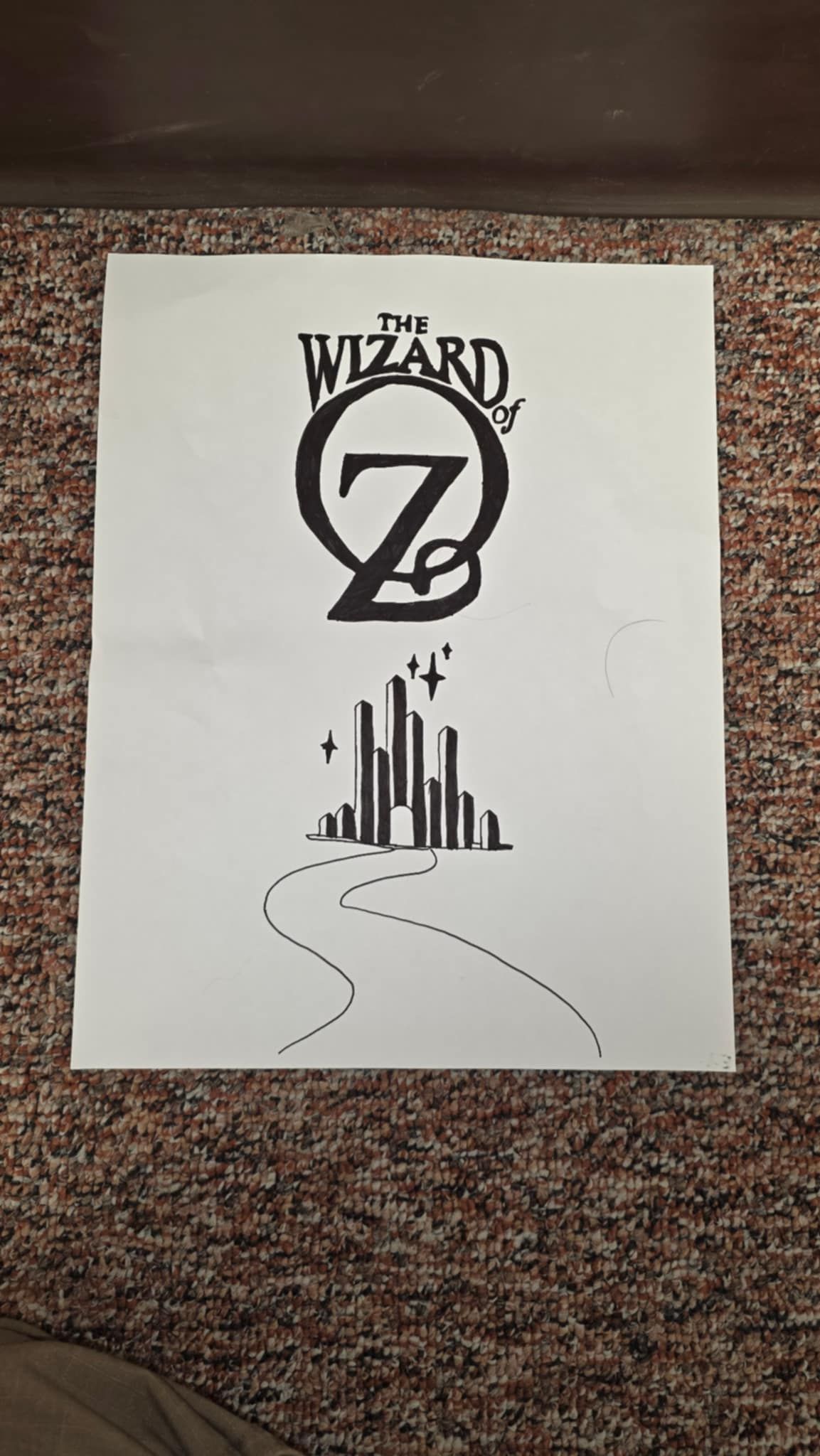 The Wizard of Oz logo with the Emerald City and a yellow brick road rendered in black on white paper.