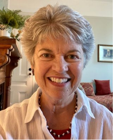 A woman is smiling in a living room with a fireplace in the background