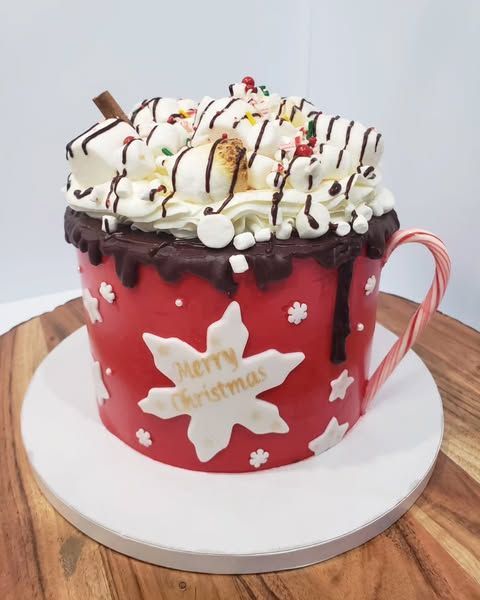 Red mug-shaped cake with white frosting and marshmallows, decorated for Christmas.