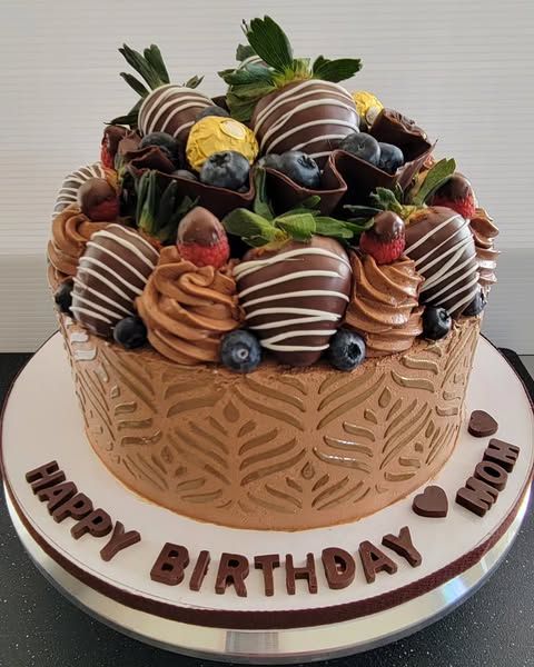 Chocolate cake decorated with chocolate-covered strawberries, blueberries, and frosting, with 