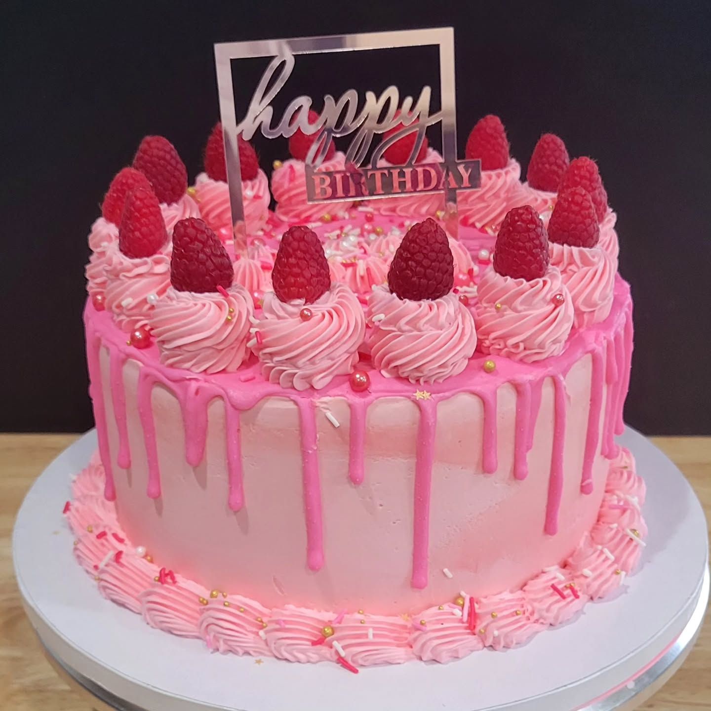 Pink birthday cake with raspberry topping and 