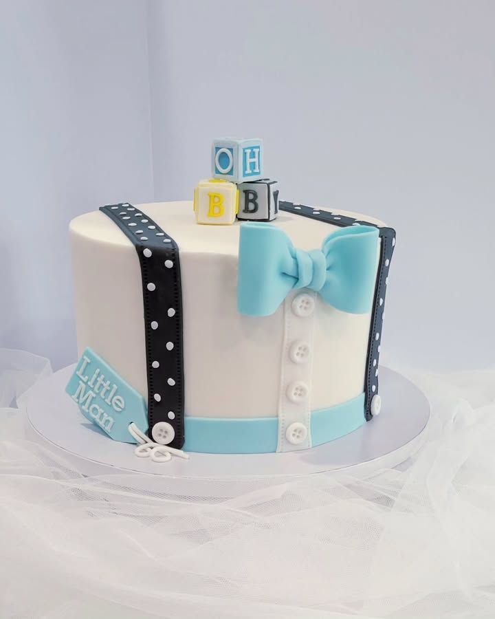 Cake decorated as a little man, featuring a bow tie, suspenders, and building blocks that spell 