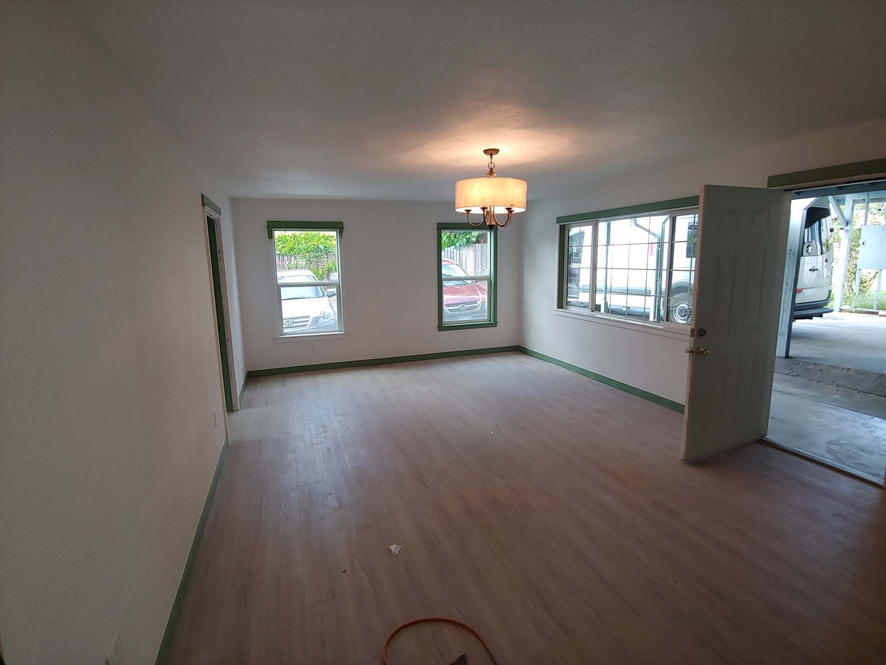 An empty living room with a chandelier and lots of windows