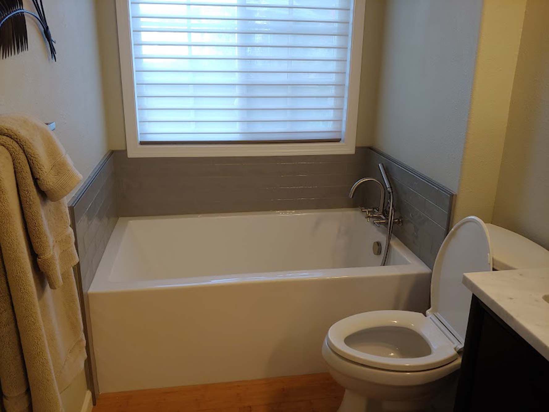 A bathroom with a tub , toilet and window.