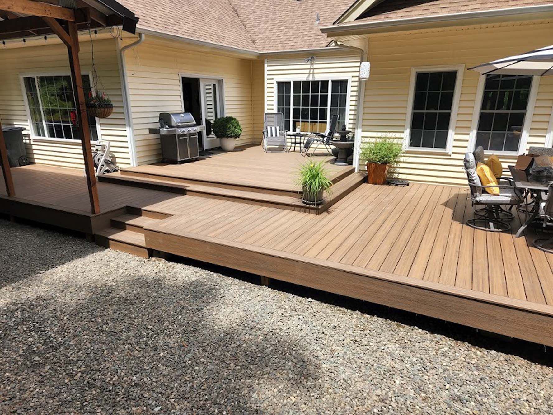 A large wooden deck is sitting in front of a house.