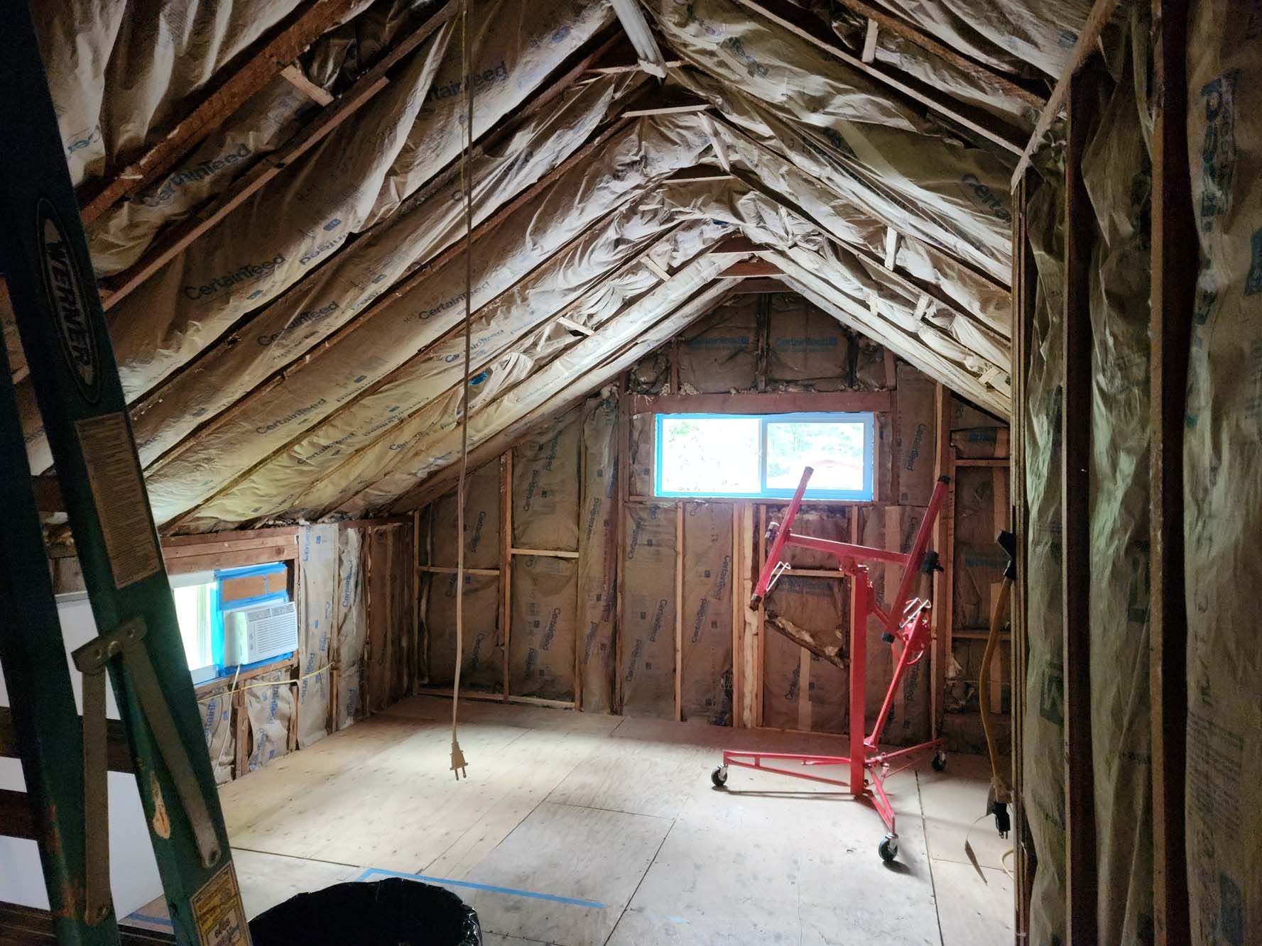 An attic with insulation and a ladder in it