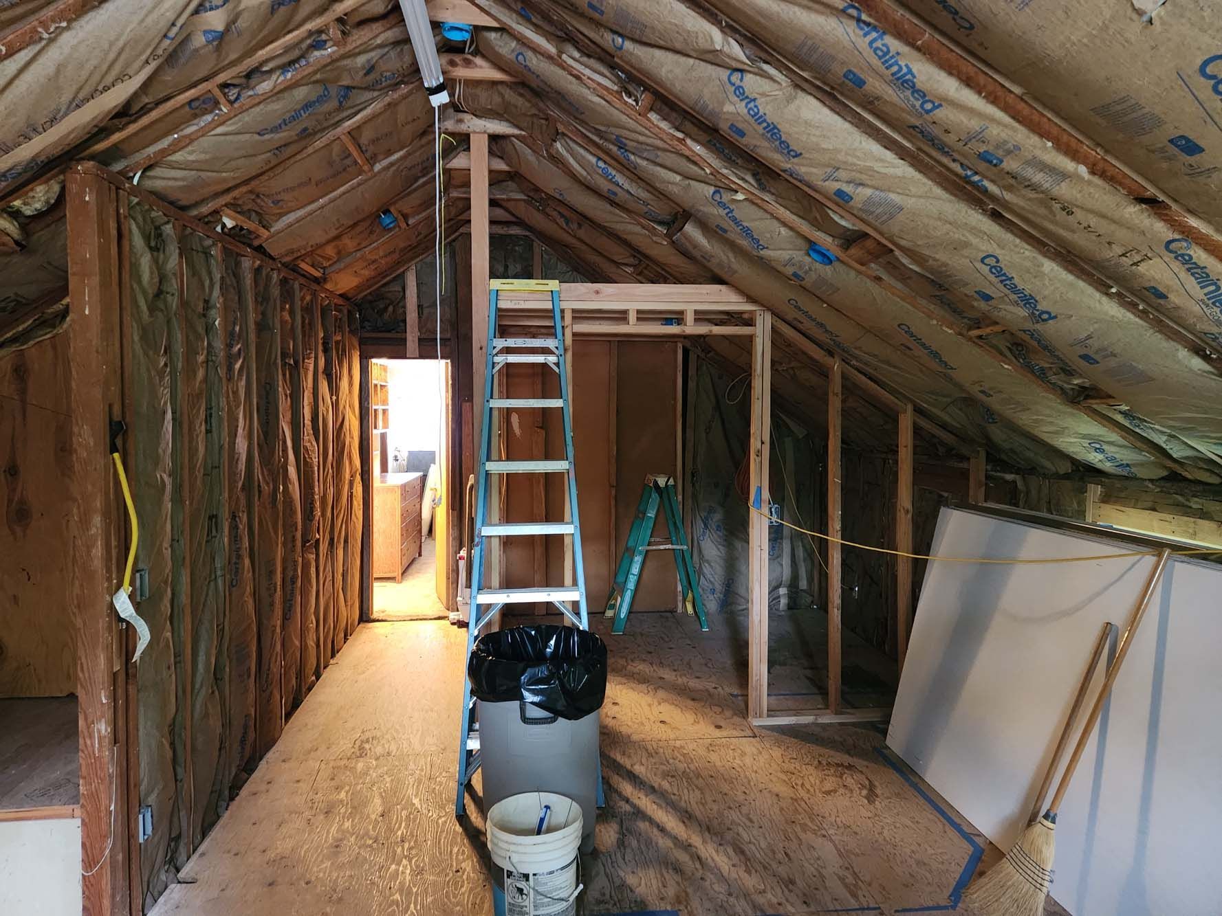 An attic with a ladder and buckets in it