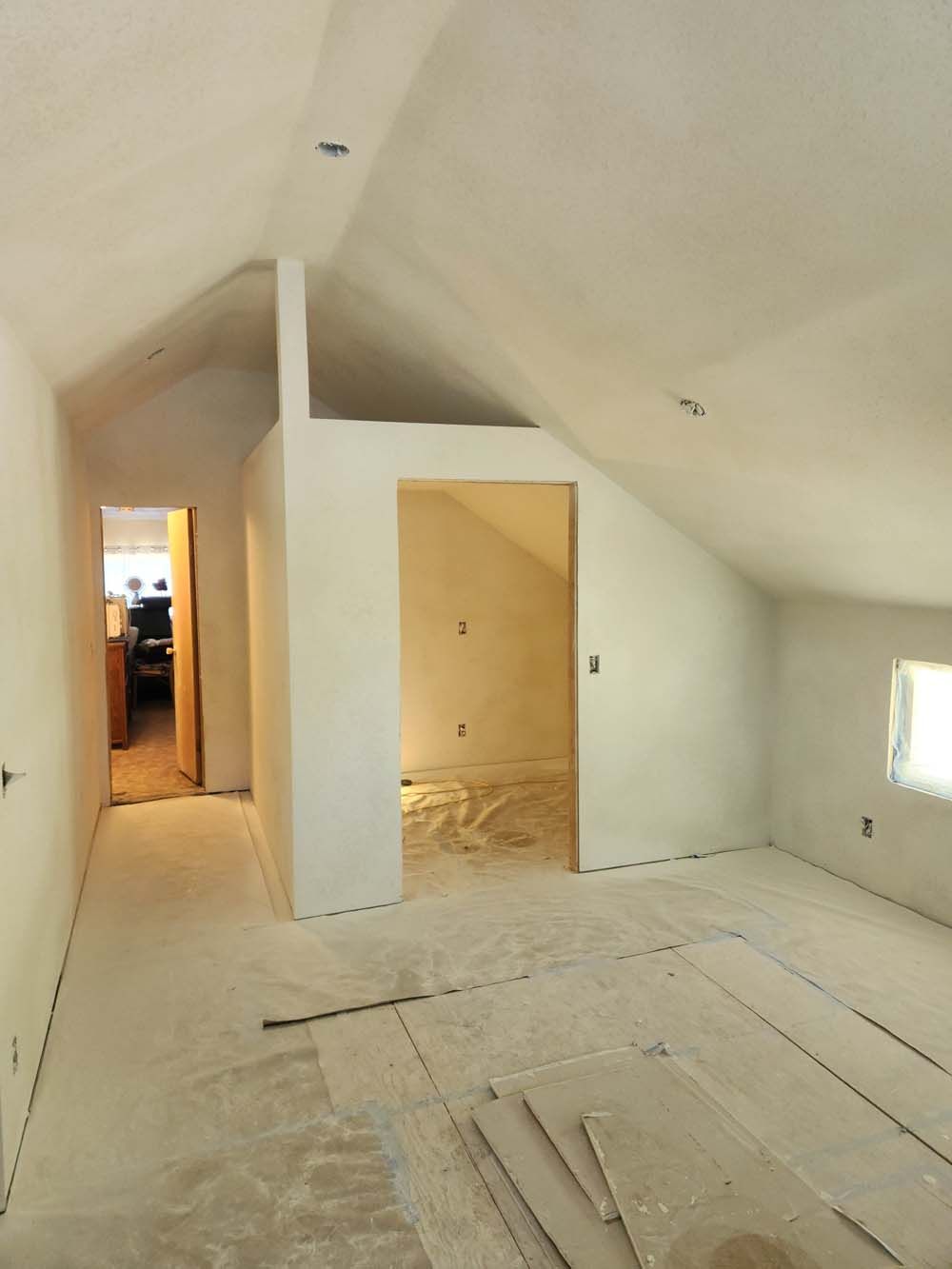 An empty room with a vaulted ceiling and white walls