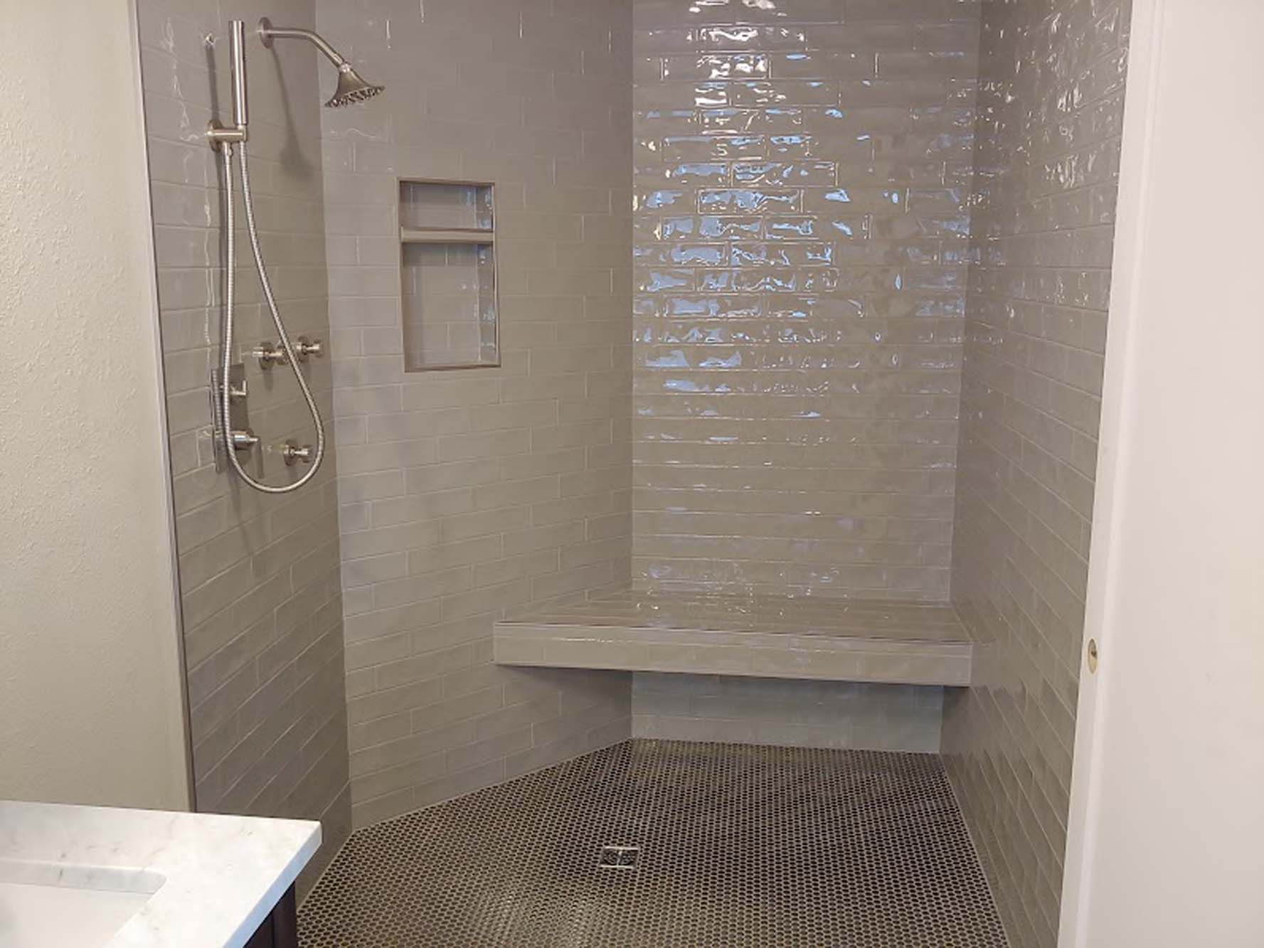A bathroom with a walk in shower and a bench.