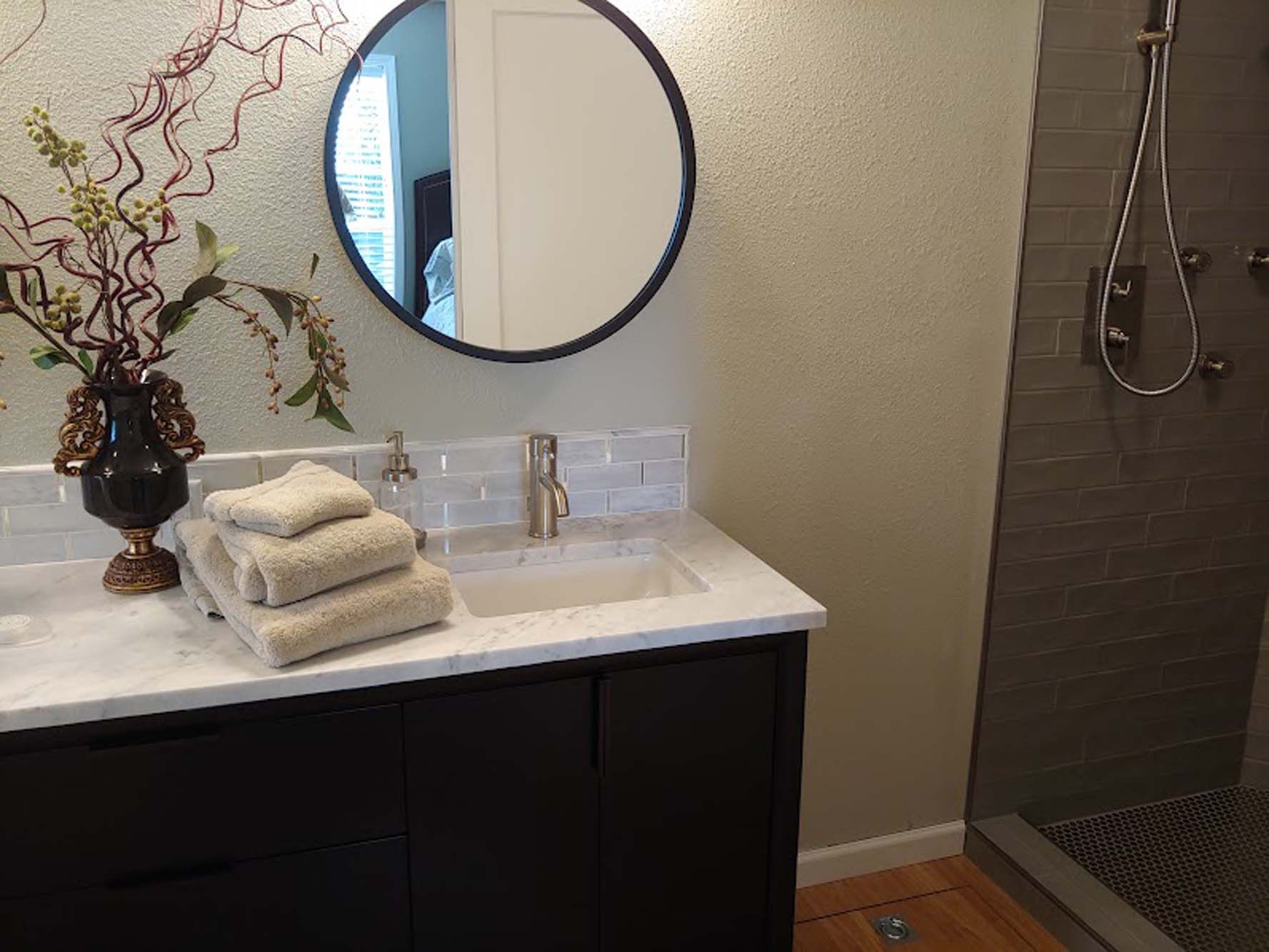 A bathroom with a sink , mirror , and shower.