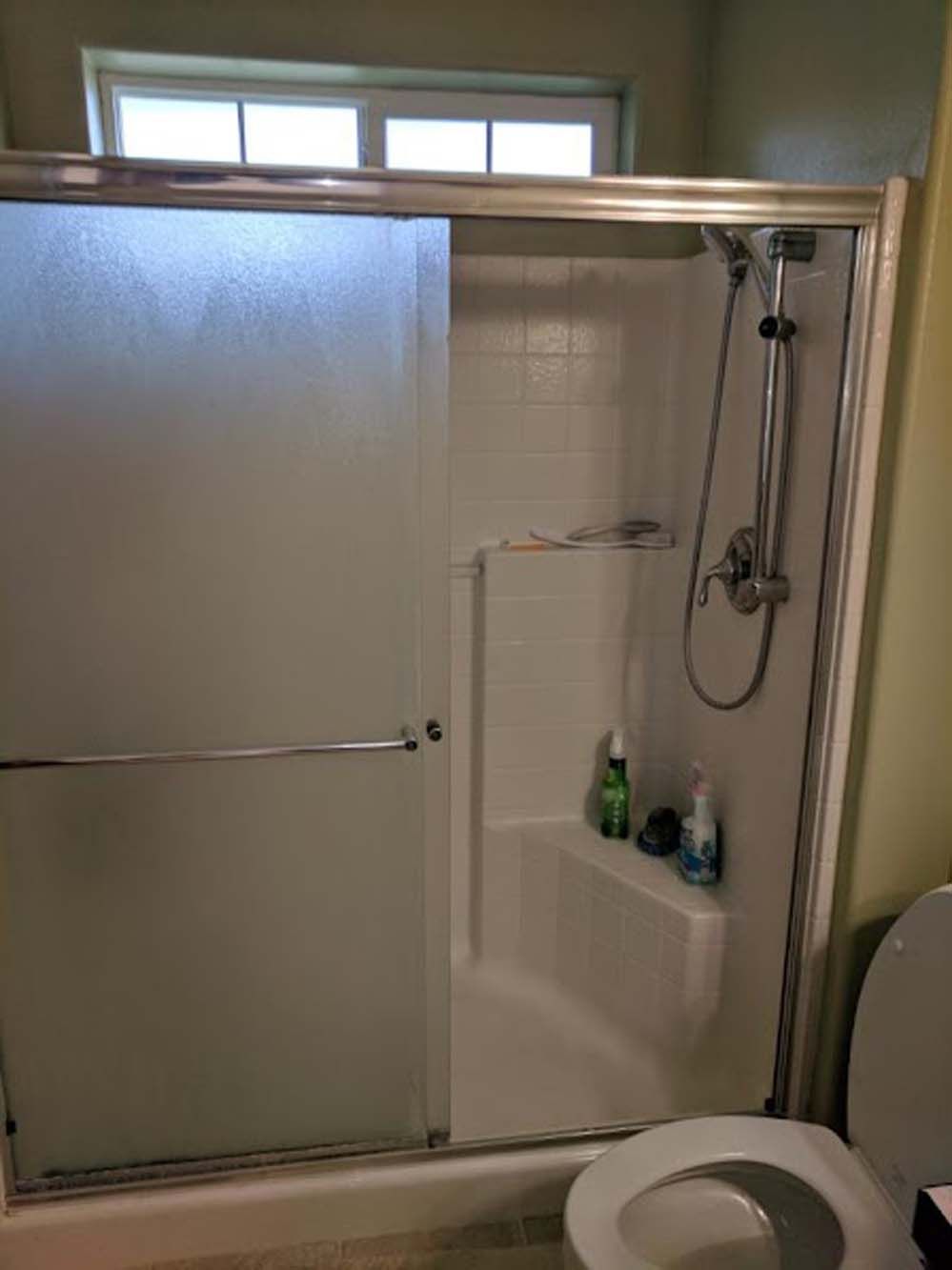 A bathroom with a sliding glass shower door and a toilet.