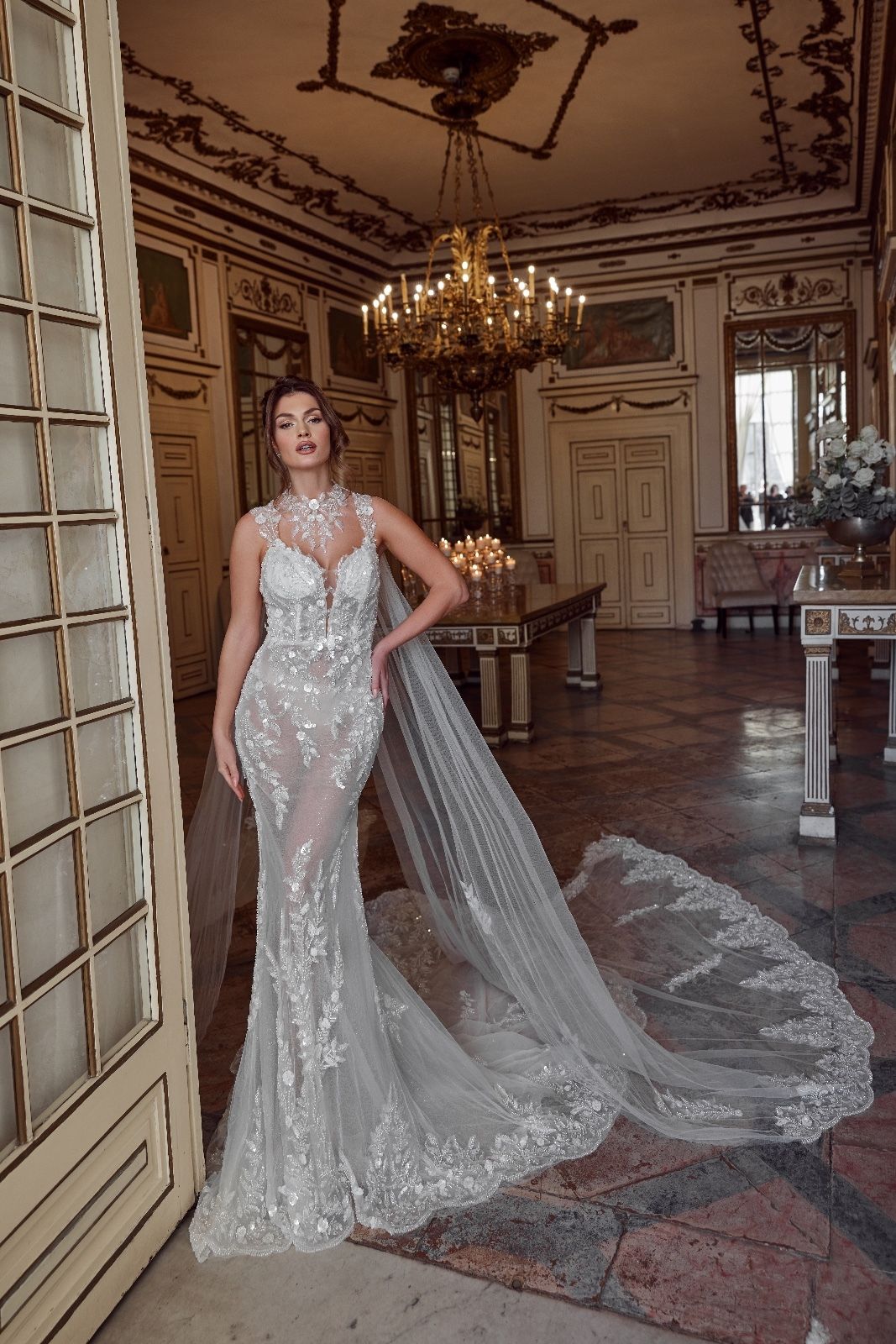 Una donna in abito da sposa è in piedi in una stanza con un lampadario.