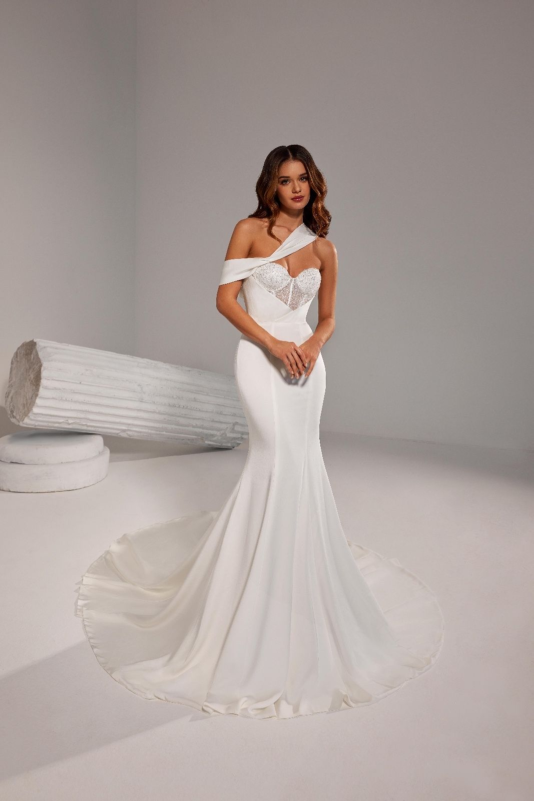 Una donna in abito da sposa bianco è in piedi davanti a una colonna bianca.