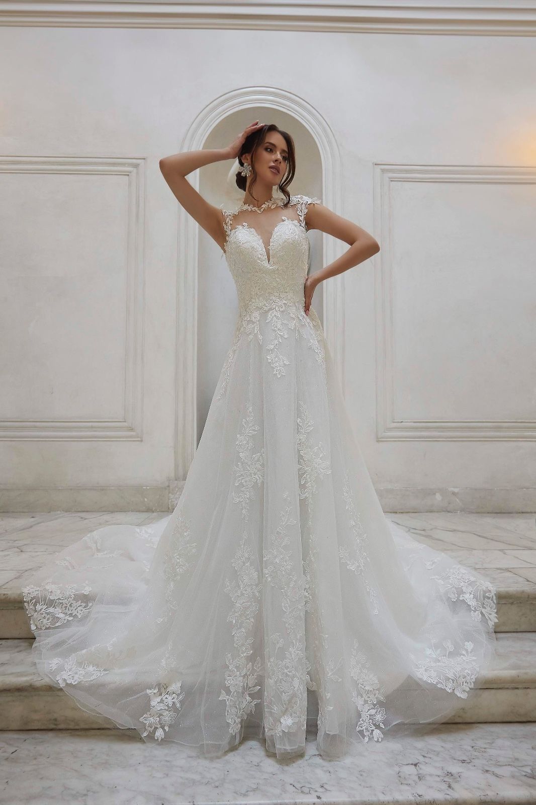 Una donna con un abito da sposa bianco è in piedi davanti a un muro bianco.