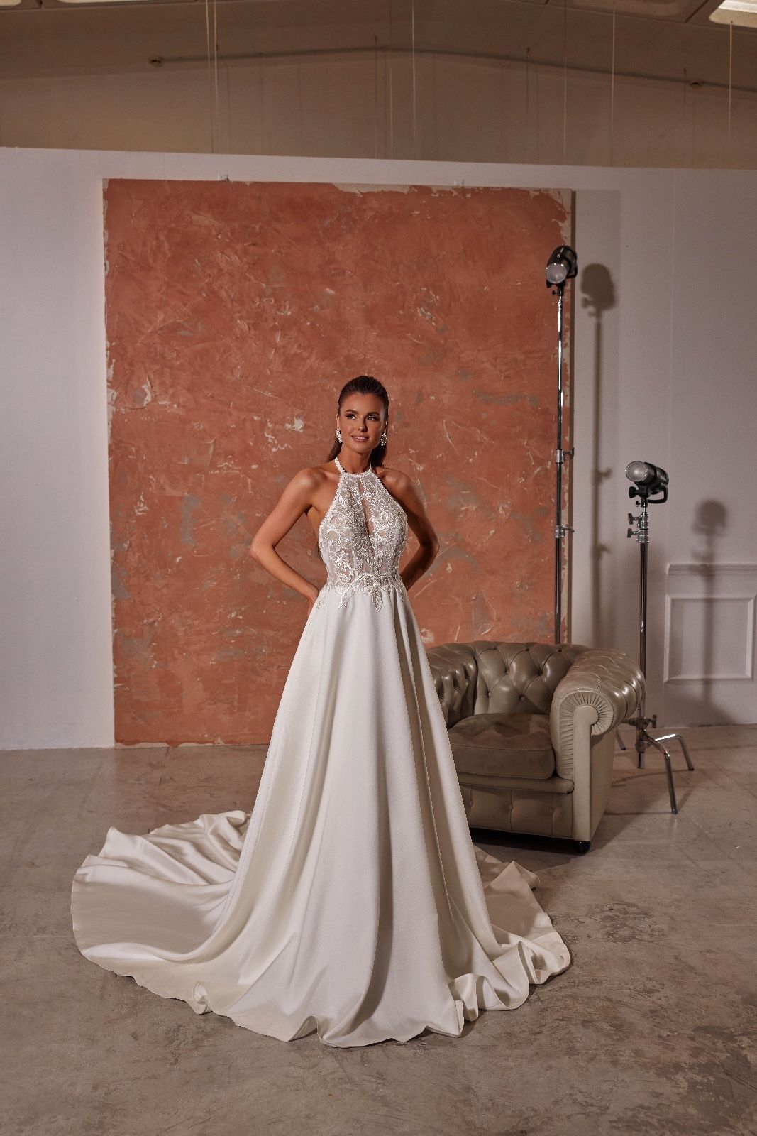 Una donna in abito da sposa bianco è in piedi davanti a un divano.